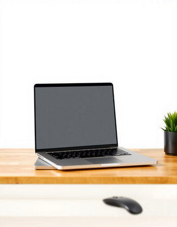 Laptop computer with blank screen on wooden table with white wall background