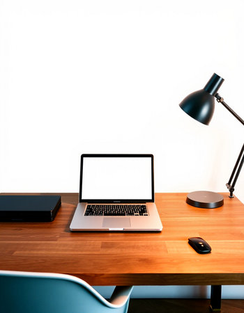 Laptop computer on wooden desk with black lamp and mouse on white wall background