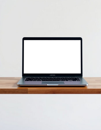 Laptop with blank screen on wooden table and white wall background.の写真素材
