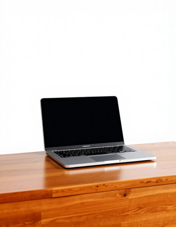 Laptop on a wooden table against a white wall with copy spaceの写真素材