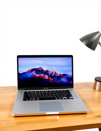 Laptop on a wooden desk with a white wall and a lamp