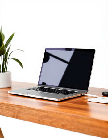 Laptop on a wooden table with a white wall in the backgroundの写真素材