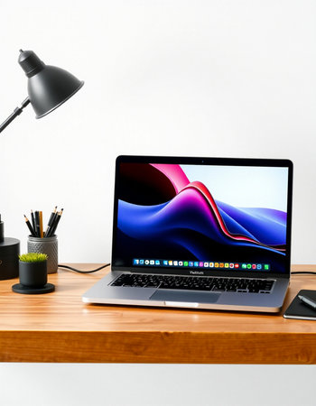 Laptop on wood table with lamp and stationery on white background