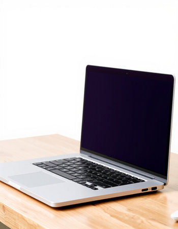 Laptop on a wooden table against a white wall with copy space