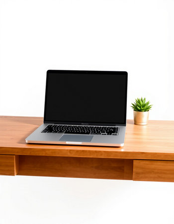 Laptop with blank screen on wooden table and white wall background.