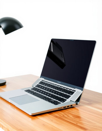 Laptop on wooden desk with black lamp and mouse on white background