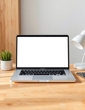 Laptop with blank screen on wooden table in office