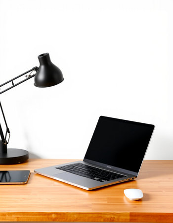 Laptop on wooden desk with lamp and mouse on white wall backgroundの写真素材