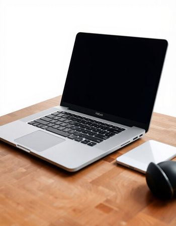 Laptop with blank screen on a wooden desk with mouse and notebook