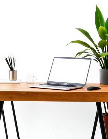 Modern workspace with laptop, coffee cup and plant on wooden table.