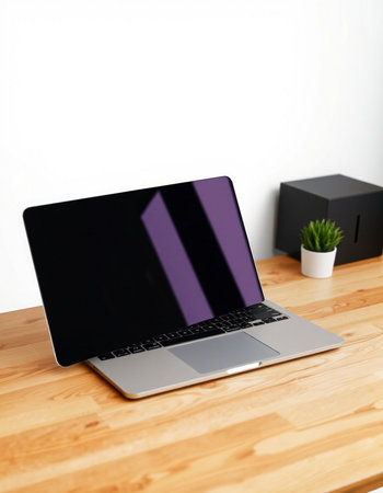 Laptop on a wooden desk with black and white wall in the backgroundの写真素材