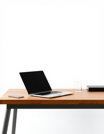 Laptop on a wooden table in front of a white wall.の写真素材