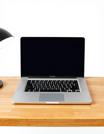 Laptop on a wooden table with a lamp and a white background