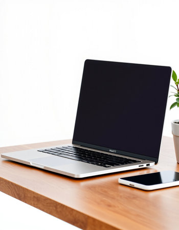 Laptop computer with blank screen on wooden table and smartphone on white background