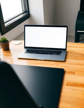 Laptop with blank white screen on wooden table in office. Mock up