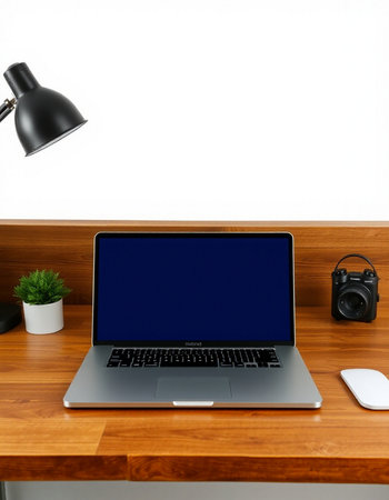 Laptop with blank screen on the wooden table and black lamp on the wall