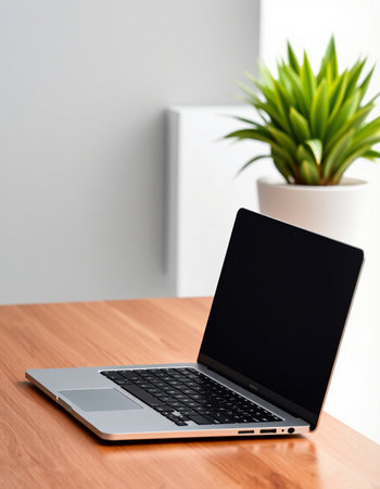 Laptop with blank screen on wooden table in office. Workplace concept
