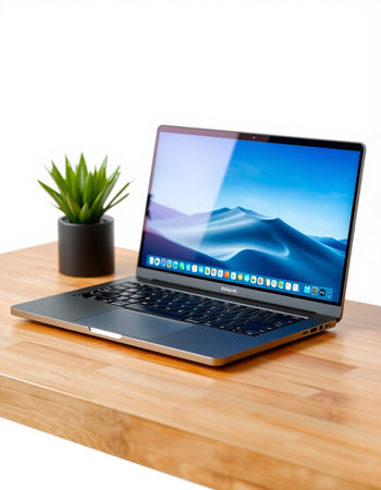 Laptop on a wooden table with a white background and a plantの写真素材
