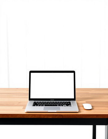 Laptop with blank screen on wood table and white wall background.