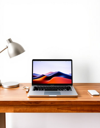 Laptop on wooden desk and white wall background.