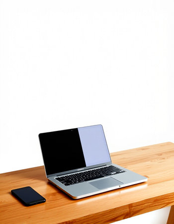Laptop and smart phone on wood table with white wall background.