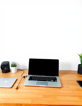 Laptop with blank screen on wooden table and white wall background.
