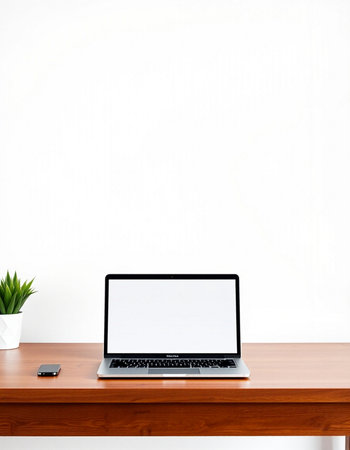 laptop with blank screen on wooden table and white wall background.