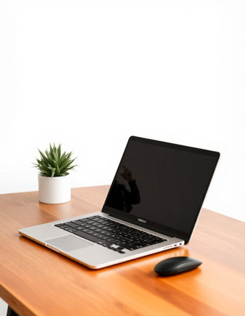 Laptop on a wooden table with a white wall in the background