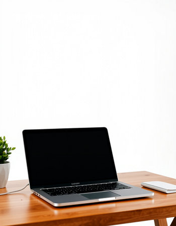 Laptop with blank screen on wood table and white wall background.