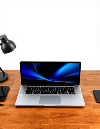 Laptop on a wooden desk with a lamp and a mobile phone