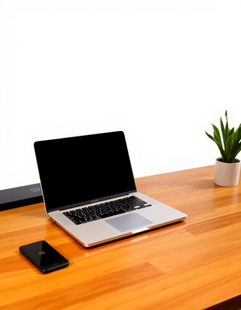 Laptop with blank screen on wood table and white wall background.