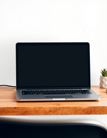Laptop on a wooden table with a white wall in the backgroundの写真素材