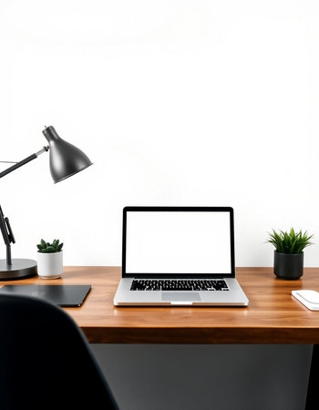 workplace with blank screen laptop on wooden table and lamp on white wall background