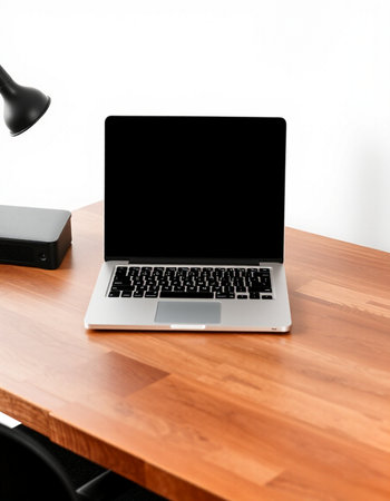 Laptop with blank black screen on wooden table. Workplace concept