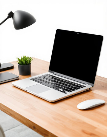 workplace with laptop, mouse, lamp and plant on wooden table