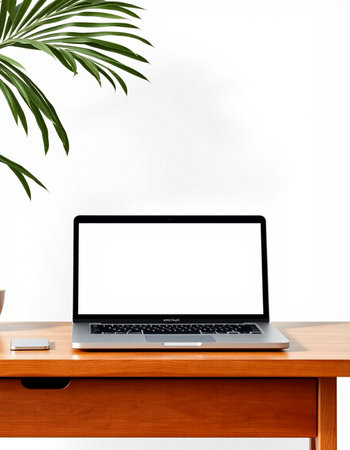 Laptop with blank screen on wooden table and plant on white wall background
