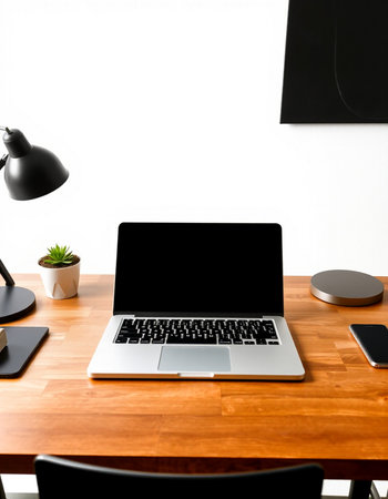 Laptop with blank screen on wooden desk in office, stock photo