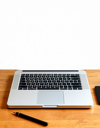 Laptop and pen on a wooden desk with white wall background.