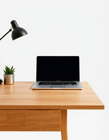 Laptop with blank screen on wooden table and lamp on white wall backgroundの写真素材