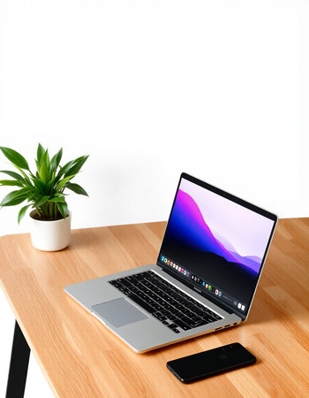 Laptop and mobile phone on wooden desk with white wall background.