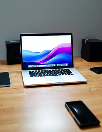 Laptop on wood table with smart phone and speaker on gray background