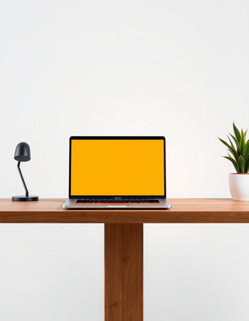 Laptop with blank yellow screen on wooden desk isolated on white backgroundの写真素材