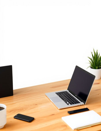 Laptop computer and office supplies on wooden table with white wall background