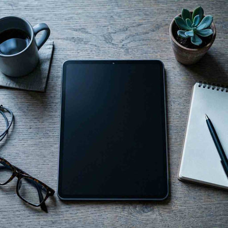 Tablet computer with blank screen and coffee cup on wooden table.