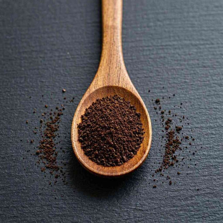 Ground coffee in a wooden spoon on a black background. Close-up.
