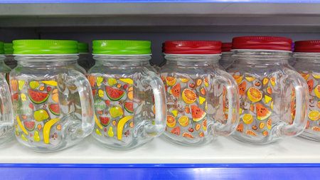 glass cups with colorful motifs and lids are displayed in a glassware shopの写真素材