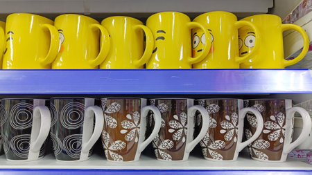 Yellow colored cups and various motifs are displayed on the glassware shelfの写真素材