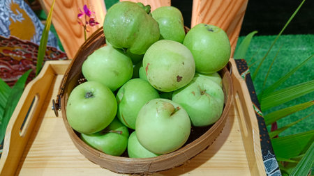 green and sweet apples in a fruit basket on a wooden trayの写真素材