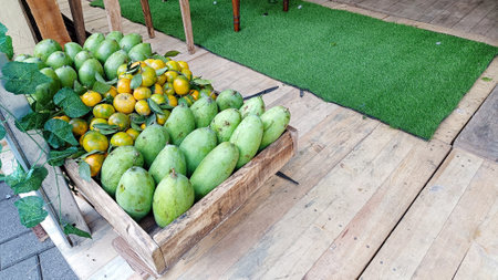 freshly harvested mangoes and oranges in wooden crates at a traditional marketの写真素材