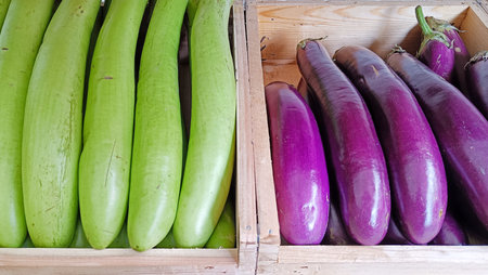 High angle view of green and purple eggplants on wooden box sale in marketの写真素材